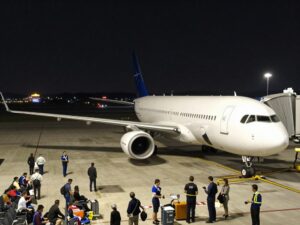 Airport runway at night with airplanes and travelers waiting due to flight delays.