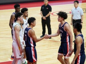 Post-game handshake between Morehouse and Tuskegee basketball teams with security presence.